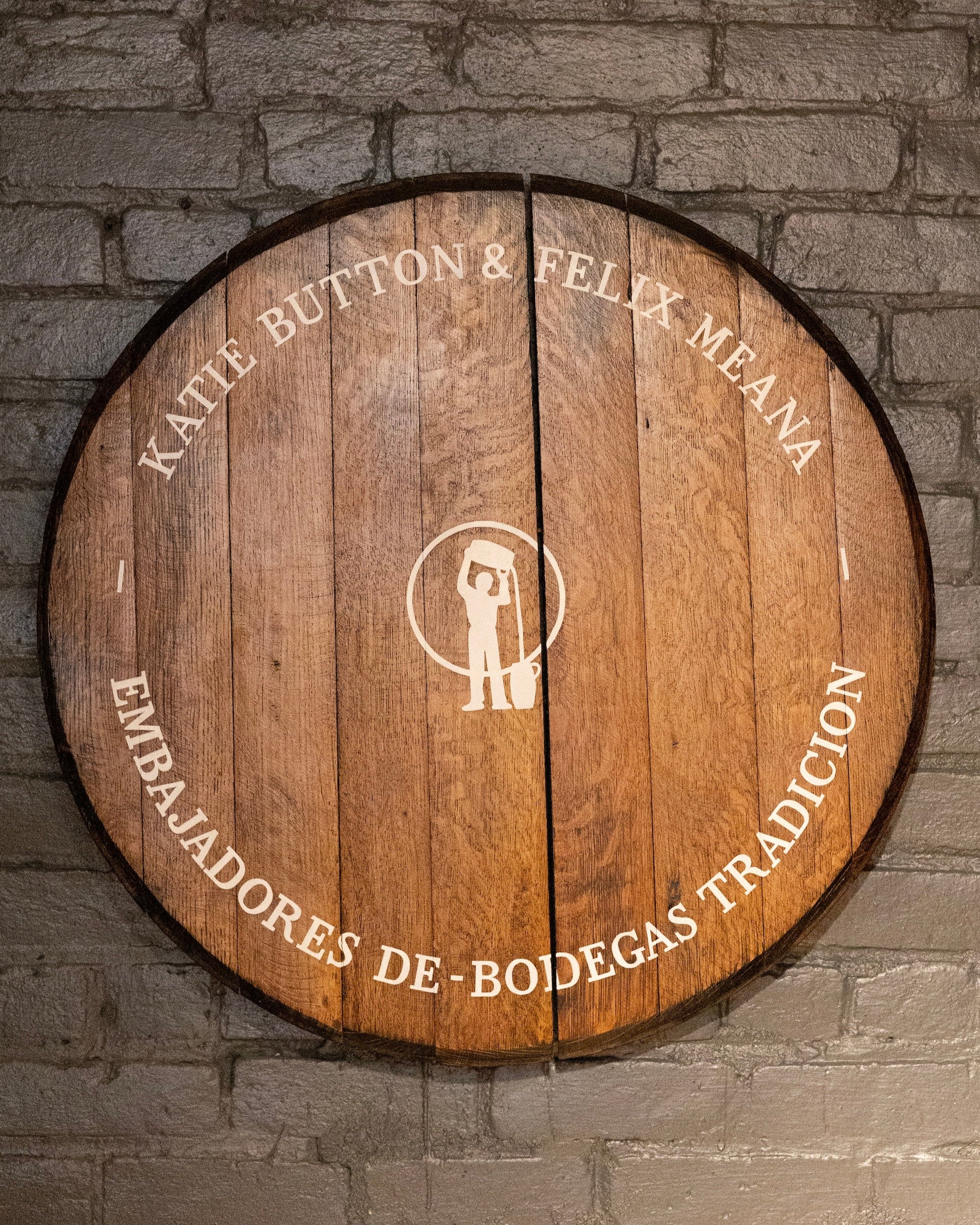 Wooden barrel with engraved text against a stone wall background