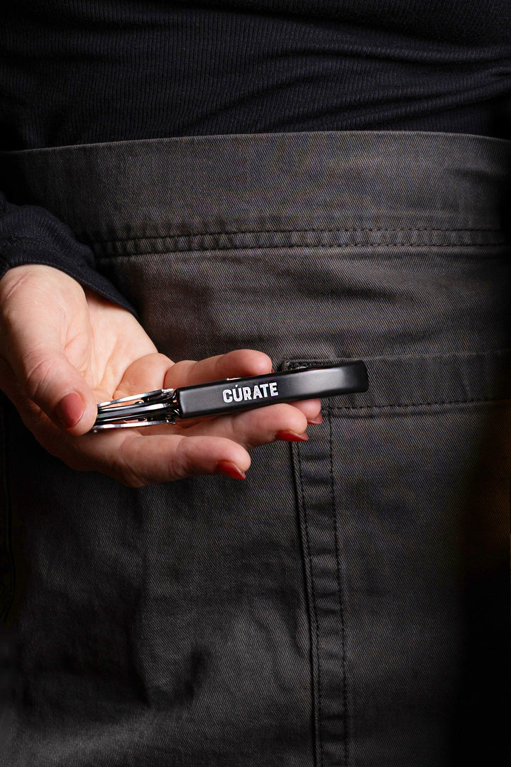 Person holding two bottles of wine with a branded apron against a brick wall.